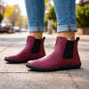 Mujer usando botas barefoot vinotinto en un entorno urbano, destacando la elegancia y confort.