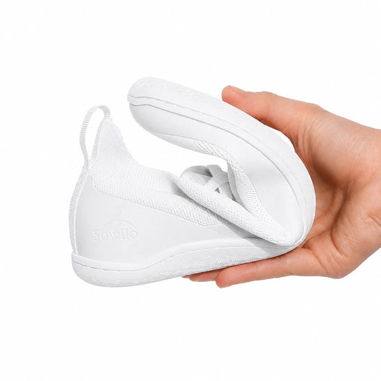 Calzado ergonómico blanco Sowilo Kenaz 100% vegano, doblado para mostrar su suela de caucho natural de 4 mm con drop cero en Chile.